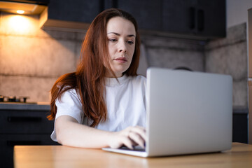 Work on the kitchen office. Remote work from home office. Young woman using laptop. Freelancer workplace at kitchen table. Distance education