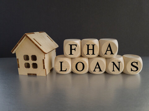 FHA federal housing administration loans symbol. Concept words 'FHA federal housing administration loans' on wooden cubes on a beautiful blak background. Model of house. Business and FHA loans concept