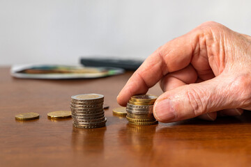 Man's hand stacking european coins on the table. Closeup.