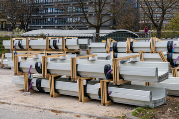 Stacked grey metal tin profiles at a construction site.