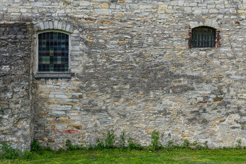 Fototapeta na wymiar Fragment of a gray stone wall with arched windows. Old antique building.