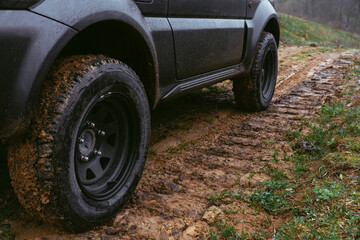 Fototapeta na wymiar An off-road vehicle with tires for all types of surfaces. Dirt and clay, country road. The mud stuck to the tread. Selective focus. Steel discs