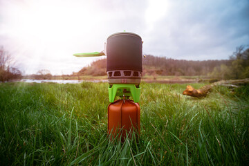 A modern gas burner, a fuel cylinder covered with a leather cover, a kettle with a protective...