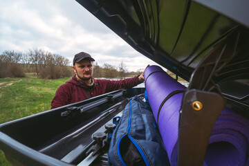 A man puts things together. Car roof rack. Tourist, camping equipment, isopropylene mat, packages with things, View from the middle. Summer day. Travel and vacation concept. © Sergey