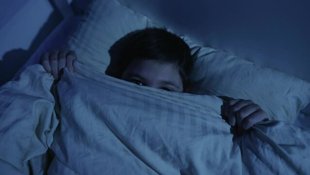 Boy covers himself with a blanket for fear at night