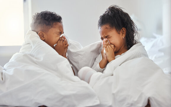Tis the season to be snotty. Shot of a brother and sister blowing their nose in bed.
