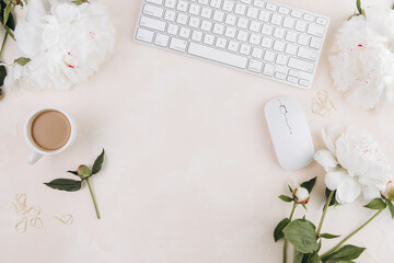 Feminine workspace with cup of coffee milk, keyboard, stylish office writing supplies and on a pastel teble