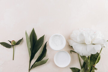 Obraz na płótnie Canvas A cream mask on a light background with a delicate peony flower. Mock up image.