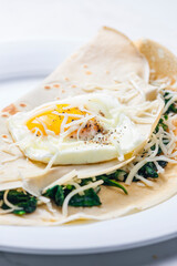 pancake stuffed with spinach leaves served with fried egg and grated cheese