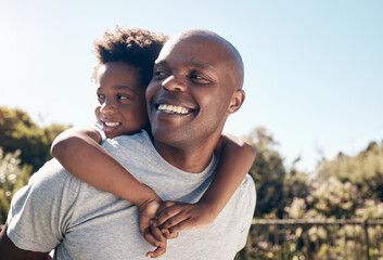 Fototapeta premium Closeup of a happy african american man bonding with his young little boy outside. Two black male father and son looking happy and positive while being affectionate and walking in a park