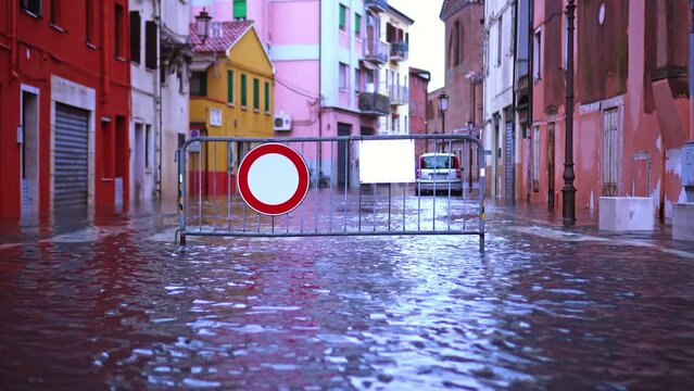 Metal fence with no-entry road sign stands among flood water