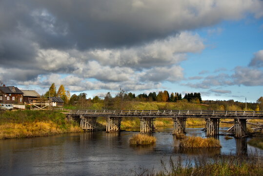Saminsky churchyard. Russia. 05 October 2018. View of the wooden bridge over the Samina River near the ancient wooden Orthodox Church of Elijah the Prophet in a picturesque place of the Vologda region