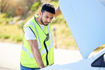 Naklejka premium Insurance is vital. Shot of an young man checking under the hood of his car after suffering a vehicle breakdown.