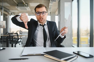 Angry senior businessman sitting at his desk and screaming