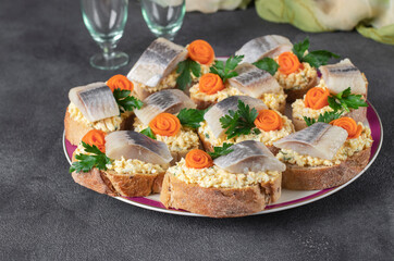 Homemade sandwiches with salted herring, cheese and egg, decorated with carrot and parsley