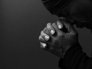 man praying to god with hands together Caribbean man praying with black background stock photos...