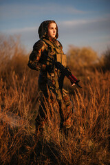 airsoft. a woman in camouflage with machine guns in her hands on the ruins.