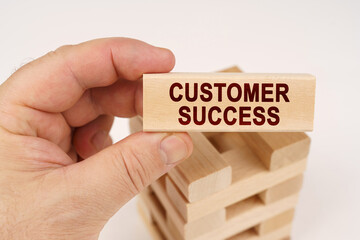 A man holds in his hands a wooden block with the inscription - Customer Success