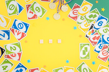 Fototapeta na wymiar Old, dirty uno cards, winner medals, empty cubes and stars on a green-yellow background.