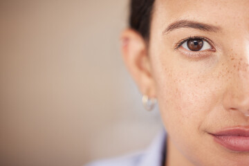 Closeup of mixed race womans eye and face with freckles split in half looking straight ahead at the camera. One female only staring in front of her. Confident woman focused on her goals and vision - obrazy, fototapety, plakaty
