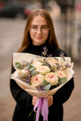 Young woman dressed in black holding in hands big flower bouquet