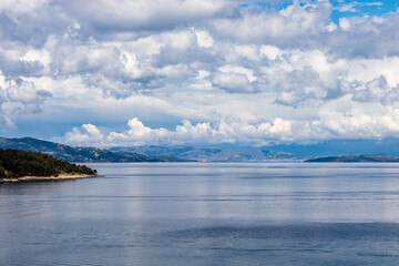 A beautiful landscape of the coast of the island of Corfu in the Ionian Sea of the Mediterranean in Greece. Pure blue clear water washes over the shores of the Greek island.