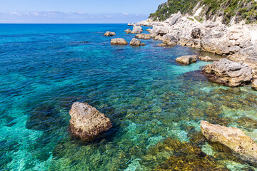 A beautiful landscape of the coast of the island of Corfu in the Ionian Sea of the Mediterranean in Greece. Pure blue clear water washes over the shores of the Greek island.