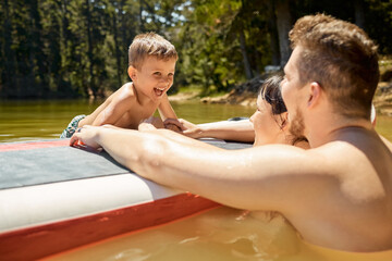 Hes having a blast. Cropped shot of an affectionate young family of three having fun in the lake.