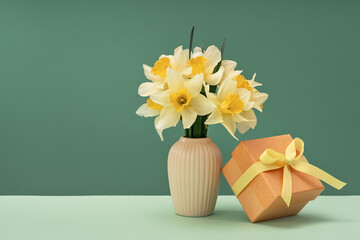 yellow daffodil flowers in ceramic vase on green. Gift box. Homemade decoration for Easter or Mothers day. Copy space.