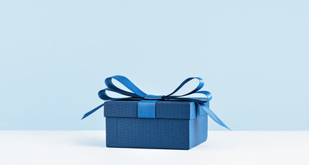 small Luxury gift box with a blue bow on light blue. Side view monochrome . Fathers day or...