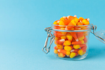 Halloween candy on a bright blue background. corn and pumpkin coffees, marmalade.Halloween holiday background with jack o lantern pumpkin, candy corn and decorations.Top view.Flat lay. Place for text.