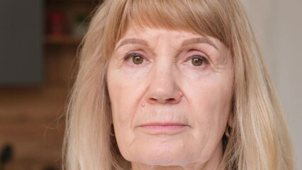 Portrait of a concentrated fair haired senior woman with closed eyes. 