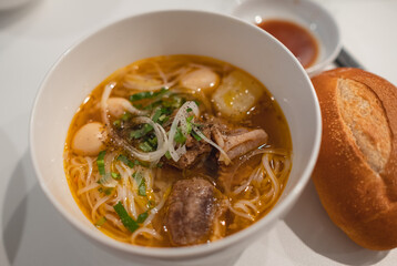 Homemade beef vegetable soup in a white bowl. Delicious noodles soup in a bowl with bread. Meat soup with vegetables