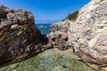 Fototapeta na wymiar A beautiful landscape of the coast of the island of Corfu in the Ionian Sea of the Mediterranean in Greece. Pure blue clear water washes over the shores of the Greek island.