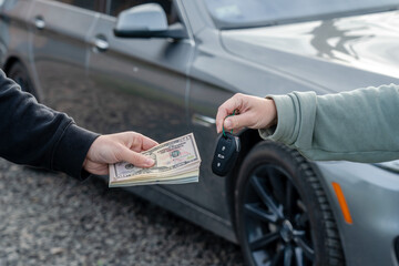 Deal of buying or renting car concept. Hand with car keys, other hand gives money.