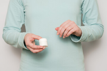 Woman's hands hold plastic jar (container). Cosmetic product.