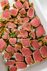 Rare Ahi tuna steak slices with carrot and herbs in white ceramic plate