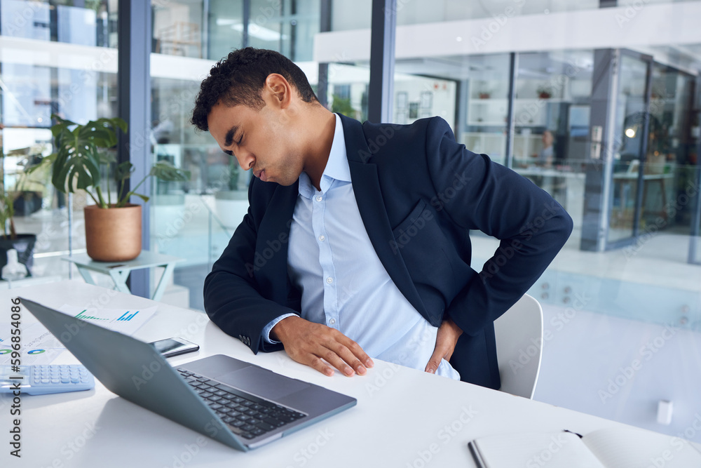 Poster the pains of working long hours. shot of a young businessman experiencing back pain while working in
