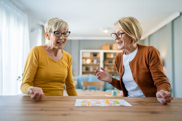 two senior women friends or sisters play leisure board game at home