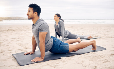 Opening up the chest while stretching the back. Shot of a sporty young couple doing an upward...
