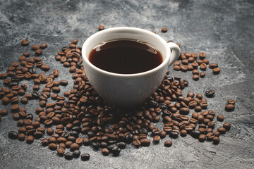 front view of brown coffee seeds with cup of coffee on dark surface textured grain group