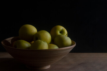 Apples in a bamboo bowl on a dark background