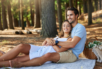 I love it when its just us. Shot of a young couple having a picnic in the forest.