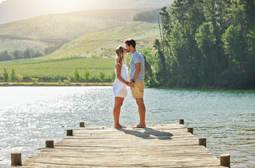 I hope this moment lasts forever. Shot of a young couple bonding while standing on a jetty at a...