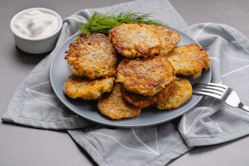 Close up view of potato pancakes. Potatoes pancakes latkes, flapjacks, hashbrown or potato vada on gray plate over gray wooden table, with fresh dill and sour cream. Copy space for text