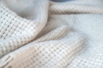 Texture of a wavy surface of a warm and cozy white woven blanket as a background