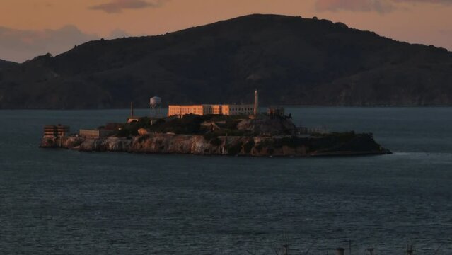 Alcatraz Island with buildings of former federal prison at dusk. Rocky island in San Francisco bay.