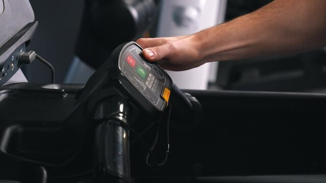 Control interface, Speed adjustment, Fitness equipment. Man's hands can be seen pushing buttons on treadmill's control panel.