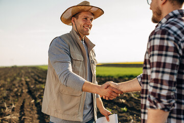 Obraz na płótnie Canvas Farmer shakes hands with his business partner in the field
