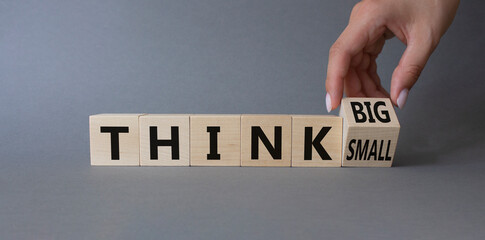 Think Big vs Small symbol. Businessman Hand turns cubes and changes words Think Small to Think Big. Beautiful grey background. Business and Think concept. Copy space